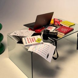 PIONA Studio Oskar Makarski - Kreatywne biurko z laptopem, aparatem, książkami o brandingu i rozwoju osobistym, oraz klapsem filmowym. Elementy graficzne i kolorystyczne na białym tle.