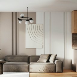 Arkush - Nowoczesny salon z beżową sofą, minimalistyczną lampą i dekoracyjną ścianą z panelami. Uwagę przykuwa abstrakcyjny obraz i drewniane szafki kuchenne w tle.
