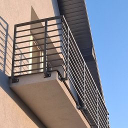 Sophia Systems - Nowoczesna, minimalistyczna balustrada balkonowa z metalowymi, poziomymi prętami, zamontowana na jasnym balkonie. Widok z dołu, błękitne niebo w tle.
