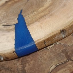 WoodCreft Zgarda - Drewniany plaster z żywicą epoksydową w kolorze głębokiego błękitu, ukazujący unikalny wzór słojów. Naturalne krawędzie kory dodają rustykalnego charakteru.