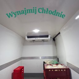 Paweł Jachymiak Góralskie Specjały - Wnętrze chłodni na wynajem w Ratułowie. Widoczny agregat chłodniczy, skrzynki z towarem i napis 'Wynajmij Chłodnie' na suficie. Czysta i gotowa do transportu.