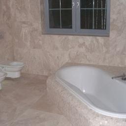 KWW-REMART Remigiusz Zagrodnik - Jasna łazienka z marmurowymi płytkami, białą wanną, bidetem i toaletą pod oknem.