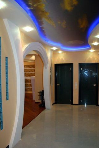 Korytarz z podświetlanym sufitem z motywem nieba, łukowatym wejściem i szklanymi elementami dekoracyjnymi na ścianie.