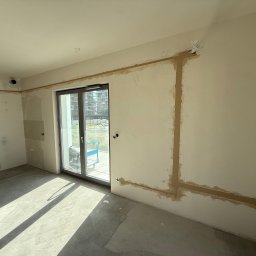 FROZE Klimatyzacja i Wentylacja - Montaż klimatyzacji w mieszkaniu: bruzdy pod instalację w ścianach, zakryte tynkiem gipsowym. Widoczne przewody i otwory. Jasne wnętrze w trakcie prac wykończeniowych.