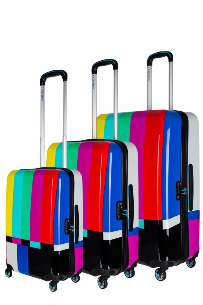 Zestaw trzech walizek na kółkach w różnych rozmiarach, z kolorowym wzorem w pionowe pasy w odcieniach żółci, zieleni, różu, czerwieni i niebieskiego, ustawionych obok siebie na białym tle.