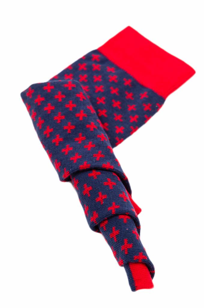 Skręcona para granatowych skarpet z czerwonymi krzyżykami i czerwonym ściągaczem, na białym tle.