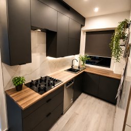 Meble SH składnie mebli - Nowoczesna kuchnia w czerni z drewnianym blatem, oświetleniem LED podszafkowym i marmurową ścianą. Minimalistyczny design z roślinami w oknie.