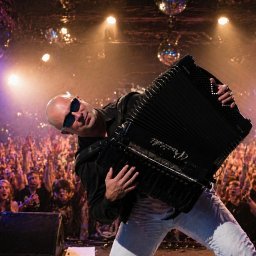 Robert Prusiński - Zespół ,DJ & Akordeon Live - Akordeonista w okularach na scenie, tłum fanów w tle, oświetlenie sceniczne i kule dyskotekowe tworzą klimat koncertu. Dynamiczne ujęcie z perspektywy widowni.
