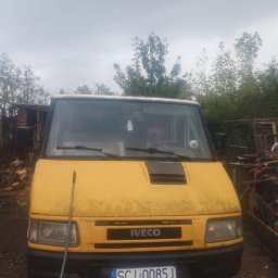 Marek Szczakowski - Żółty samochód dostawczy marki Iveco z widoczną tablicą rejestracyjną SCI 0085J, zaparkowany na zewnątrz w pochmurny dzień, z widocznymi drzewami w tle.