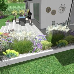 Niwińska Sarkiewicz Ogrody i Wnętrza - Wizualizacja ogrodu z tarasem, ozdobne trawy i kwiaty wzdłuż białego obrzeża, meble ogrodowe na szarym tarasie, dekoracje ścienne, kobieta w tle.