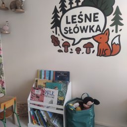 Leśne Słówka - Pokój logopedyczny z regałem pełnym książek dla dzieci, pluszowym lisem na ścianie i workiem z zabawkami. Przytulne, edukacyjne wnętrze.