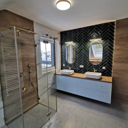 EDBUD.COMPANI - Nowoczesna łazienka z kabiną prysznicową typu walk-in, podwójną umywalką na szafce w kolorze błękitu i czarną ścianą z płytek ułożonych w jodełkę.