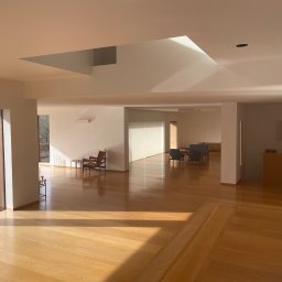 sppserwis - Jasne, przestronne wnętrze z drewnianą podłogą i białymi ścianami. Widoczne meble w stylu skandynawskim i wpadające promienie słoneczne. Minimalistyczny design.