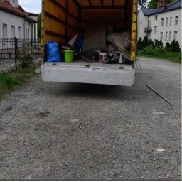 Ekipa Szybkiego Sprzątania - Otwarta paka samochodu dostawczego wypełniona workami, wiadrem i różnymi przedmiotami, prawdopodobnie przeznaczonymi do utylizacji. Widok z tyłu pojazdu.