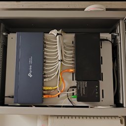 Bartosz Lewicki - Szafa rack z zamontowanym switchem TP-Link TL-SG116 i okablowaniem sieciowym. Widoczne porty Ethernet i światłowodowe. Estetyczne ułożenie kabli wewnątrz szafy.