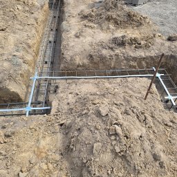 Elflow Maciej Zawiasa - Uziemienie budynku w trakcie realizacji: wykop z płaskownikiem ocynkowanym, widoczne punkty wyprowadzone do rozdzielni i instalacji odgromowej. Prace ziemne.