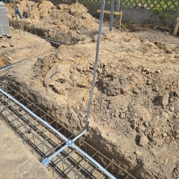 Elflow Maciej Zawiasa - Uziom fundamentowy z płaskownika ocynkowanego w wykopie, przygotowany do zalania betonem. Widoczne zbrojenie i wyprowadzenia do instalacji odgromowej.