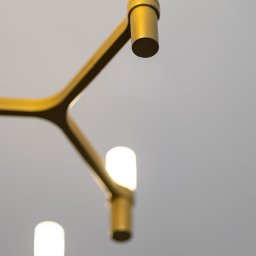 ARCHITEKSTURA Malwina Kroll architekt - Złoty, nowoczesny żyrandol z trzema świecącymi, cylindrycznymi lampami na tle jasnego sufitu. Minimalistyczny design, ciepłe światło.
