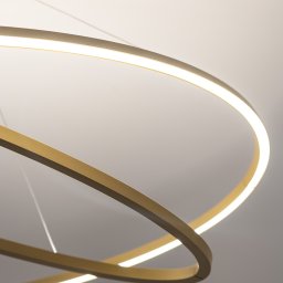 ARCHITEKSTURA Malwina Kroll architekt - Nowoczesna lampa sufitowa LED z trzema złotymi okręgami, delikatne światło, minimalistyczny design, widok z dołu, szare tło.