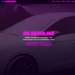 KreativSEO - Strona internetowa firmy RS Detailing z białym samochodem pokrytym pianą, mytym przez osobę w tle. Neonowe logo i przyciski rezerwacji wizyty.