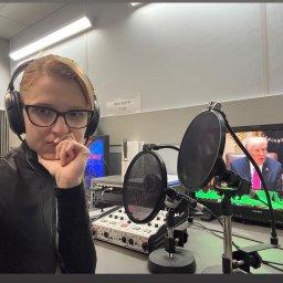 Yana Shevchuk - Kobieta w słuchawkach, w studiu nagrań, z ekranem pokazującym Donalda Trumpa. Biuro czynne 7-23. Mikrofony z filtrami pop. Sprzęt audio. Profesjonalne tłumaczenia symultaniczne.