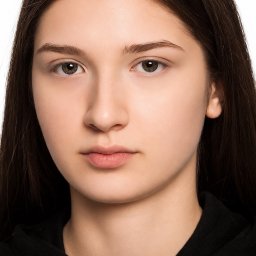 Yuliia Hrushko - Portret młodej kobiety z brązowymi włosami i oczami, bez makijażu, na białym tle. Ujęcie centralne, skupiające się na twarzy i naturalnym wyglądzie.