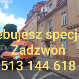 BMT - Pomarańczowy podnośnik koszowy na tle budynku. Nałożony tekst reklamowy z numerem telefonu. Usługi na wysokościach w przestrzeni miejskiej.