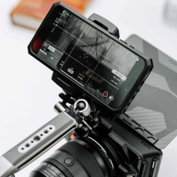 FMD.studio - Aparat z obiektywem Sony FE 1.2/50 GM i smartfonem Marshall na uchwycie, ustawienia ISO 1000 i migawki 1/125, na białym tle z książką w tle.