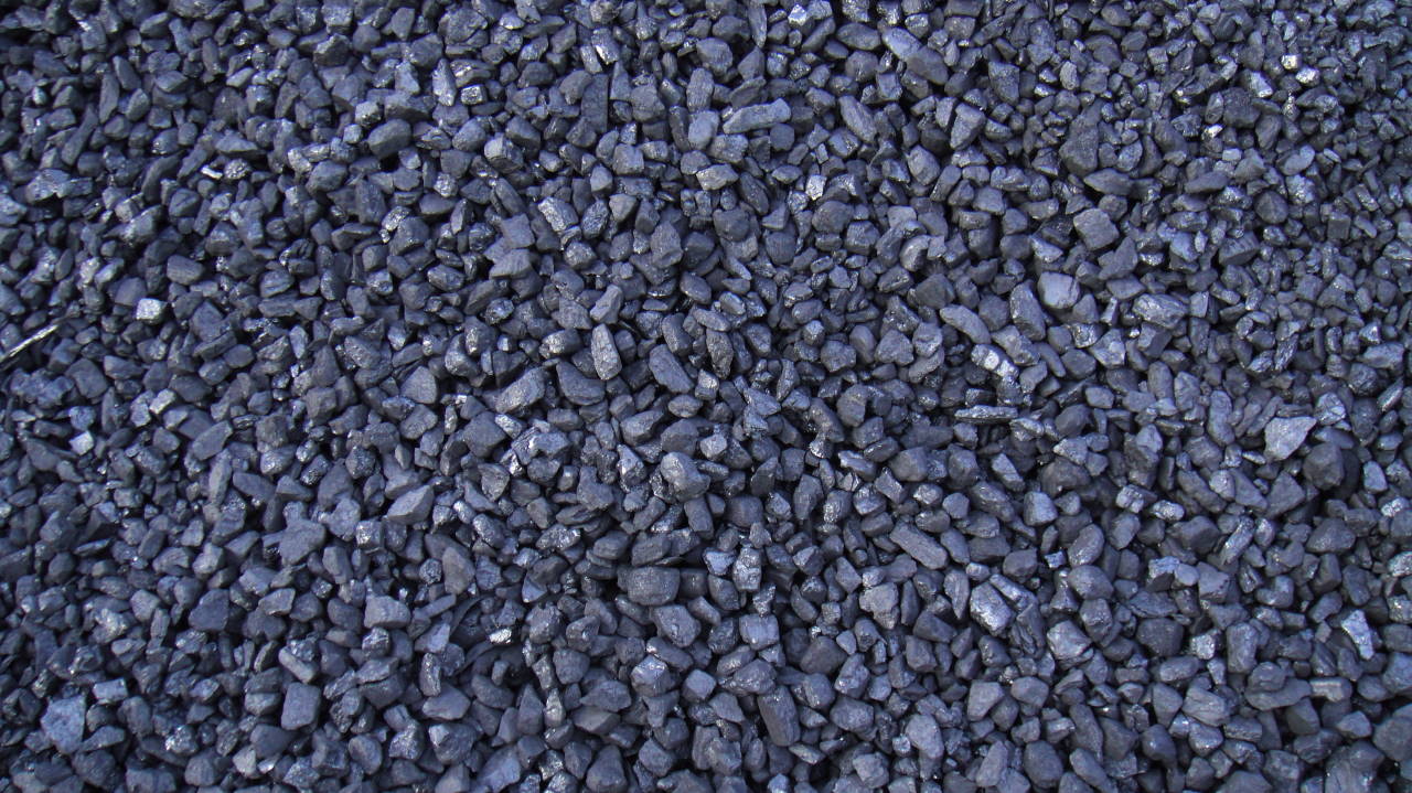 Kupa antracytu o różnej wielkości ziarnach, z widocznymi refleksami światła.