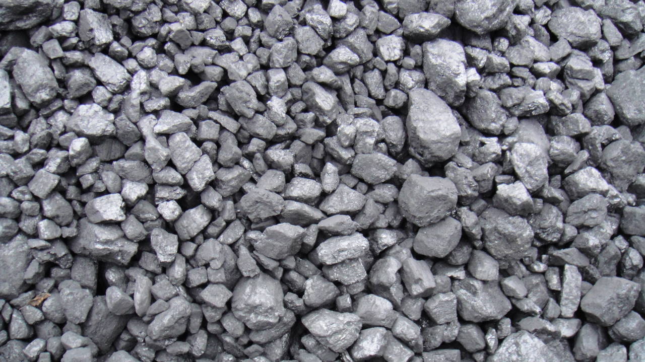 Kupa węgla orzech, z widocznymi nieregularnymi bryłami o błyszczącej powierzchni i różnej wielkości, tworząc zwartą teksturę.