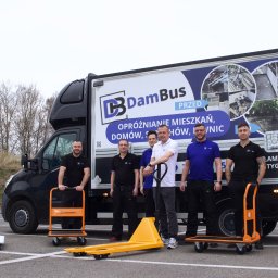 DB DamBus - Ekipa firmy DamBus z wózkami transportowymi przed busem z grafiką 'Opróżnianie mieszkań, domów, strychów'. Widoczne zdjęcia 'przed' opróżnianiem.