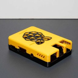 Kamil Czernik - Żółto-czarna obudowa Raspberry Pi z logo maliny, wykonana metodą druku 3D. Widoczne otwory wentylacyjne i porty. Gładka powierzchnia, precyzyjne wykonanie.