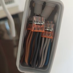 Marcel Konicki - Zbliżenie na puszkę instalacyjną z przewodami połączonymi złączkami WAGO. Widoczne przewody w różnych kolorach. Biała puszka montażowa.