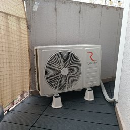 RAF-MART - Biała jednostka zewnętrzna klimatyzacji Rotenso ELIS Series, zamontowana na balkonie w Nowej Rudzie, z widocznymi wspornikami i elementami instalacji.