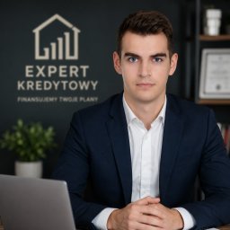 Patryk Jankowski - Pośrednictwo Finansowe - Portret mężczyzny w garniturze na tle biura z logo 'Expert Kredytowy', sugerujący doradztwo finansowe. Widoczny laptop i roślina doniczkowa.