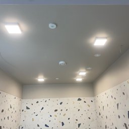 PRIME SERVICE - Nowoczesna łazienka z kwadratowymi lampami sufitowymi LED i czujnikami dymu, ściany wyłożone płytkami w stylu lastryko. Oświetlenie równomierne.