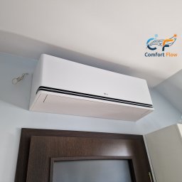 Comfort Flow - Biały klimatyzator LG zamontowany w pomieszczeniu w Chrzanowie. Widoczny fragment drzwi i szafki. Logo firmy w prawym górnym rogu.