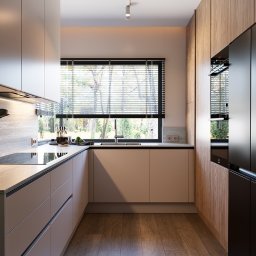 AM design Anna Mrugała - Nowoczesna kuchnia w beżach i drewnie: minimalistyczne szafki, okno z żaluzjami i wbudowany sprzęt AGD. Ujęcie z rośliną w rogu kadru.