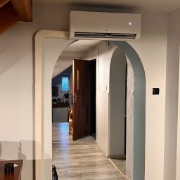 Cold-Dys - Biały klimatyzator LG z wyświetlaczem '16' zamontowany nad łukowym przejściem w jasnym wnętrzu. Widoczna estetyczna maskownica instalacji biegnąca wzdłuż ściany.