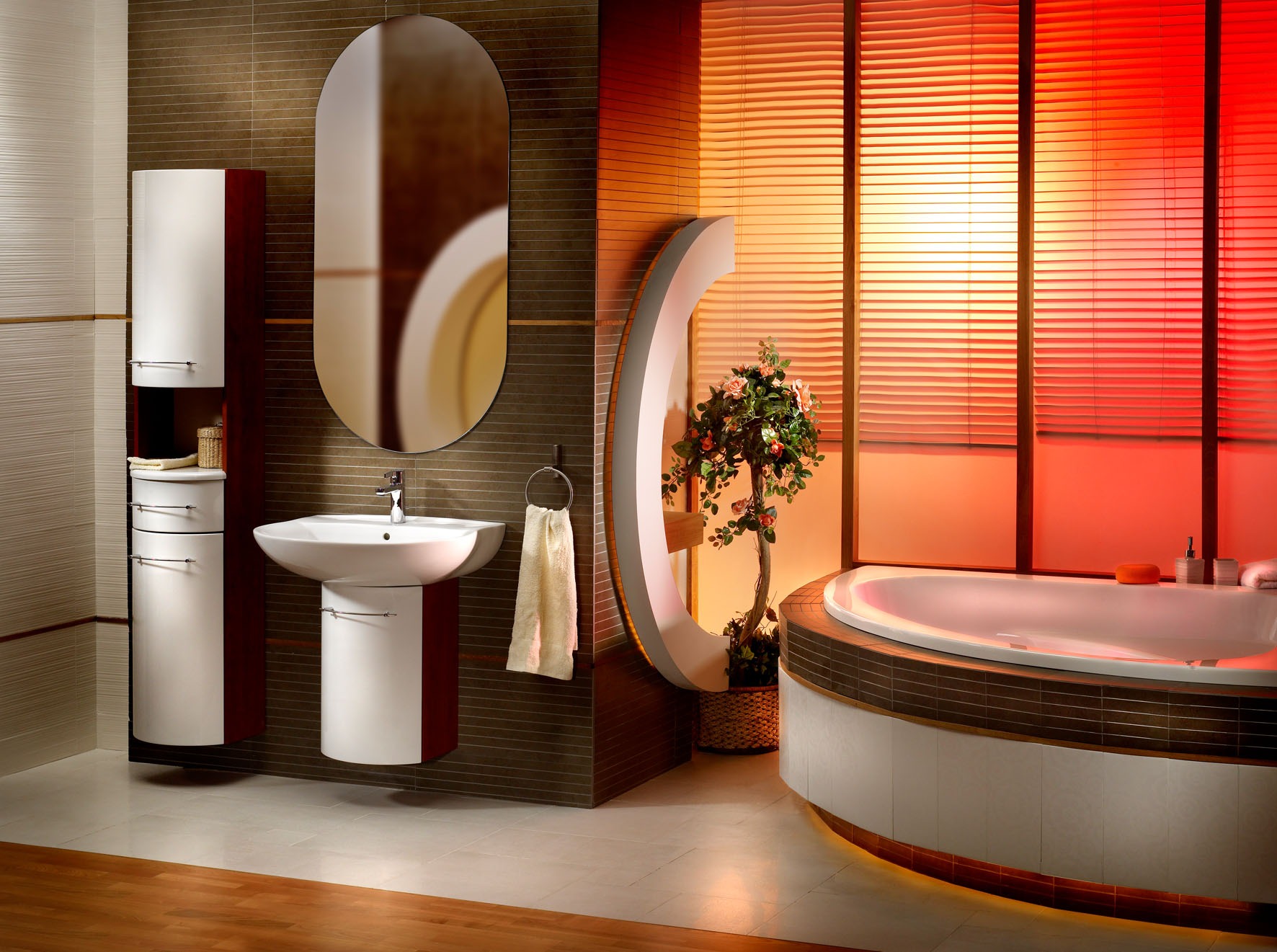 Nowoczesna łazienka z owalnym lustrem, białą umywalką na postumencie, szafką wiszącą i okrągłą wanną, oświetlona czerwonym światłem.