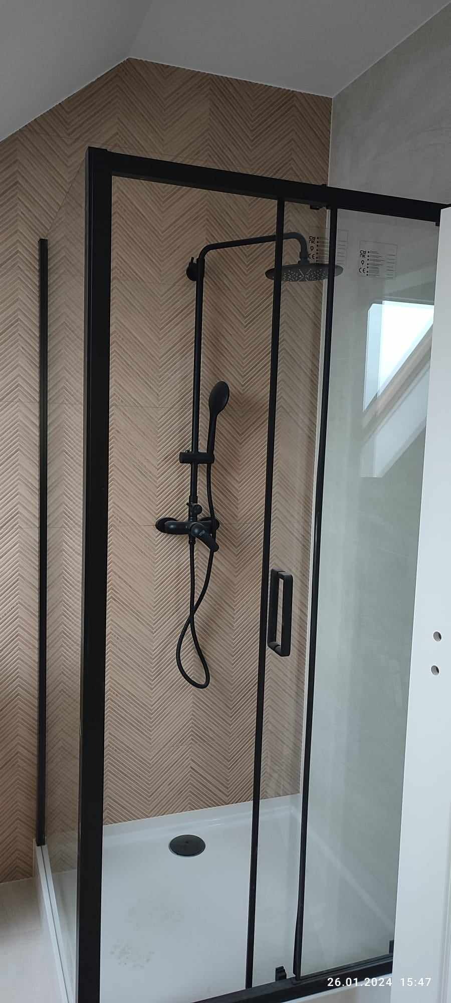 Nowoczesna kabina prysznicowa z czarną armaturą i geometryczną tapetą w beżowych odcieniach.