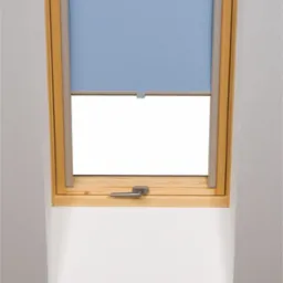 Okno dachowe z częściowo opuszczoną, błękitną roletą tekstylną, drewniana rama okienna, widoczny metalowy uchwyt okna.