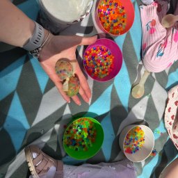 Creative Time - Kolorowe kulki w miseczkach i w dłoni, dziecięca zabawa na kocu w plenerze. Przygotowania do animacji z wykorzystaniem sensorycznych kulek wodnych.