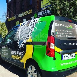 Kiwi Gifts Drukarnia Reklama - Okolicznościowo oklejony samochód firmowy z grafiką wiertła i hasłem 'Geolog wierci najgłębiej', prezentujący usługi geologiczne, geofizyczne i badania środowiskowe.