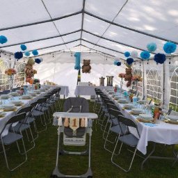 All4events - Biały namiot eventowy z dekoracjami na pierwsze urodziny: stoły z nakryciami, złote podkładki, szare krzesła, niebieskie pompony, balony misie i cyfra '1'. Uroczystość na trawie.