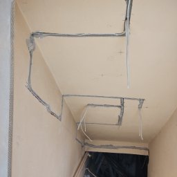 Jakub Śpiewak - Ułożone przewody elektryczne w bruzdach ściennych i sufitowych, z widocznymi peszlami i listwami narożnikowymi, przygotowanie pod tynkowanie.