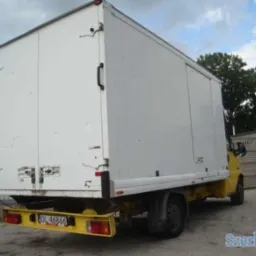 Żółto-biały samochód dostawczy z zabudową kontenerową, widok z tyłu, tablica rejestracyjna DL 46866, zaparkowany na placu.