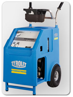 Niebieska przecinarka linowa Tyrolit Hydrostress na kółkach, z widocznymi manometrami i panelem sterowania, gotowa do wiercenia otworów i cięcia ścian.