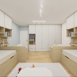 DP STUDIO Alina Wróbel - Symetryczny pokój dziecięcy z dwoma łóżkami z szufladami, biurkami i półkami na książki. Centralna szafa, jasne drewno i białe fronty. Niebieski i różowy zagłówek.