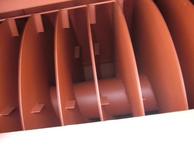 Wnętrze suszarni biomasy: rzędy metalowych, zakrzywionych przegród wewnątrz urządzenia, widoczne elementy konstrukcyjne, pomalowane na jednolity, brązowo-czerwony kolor.